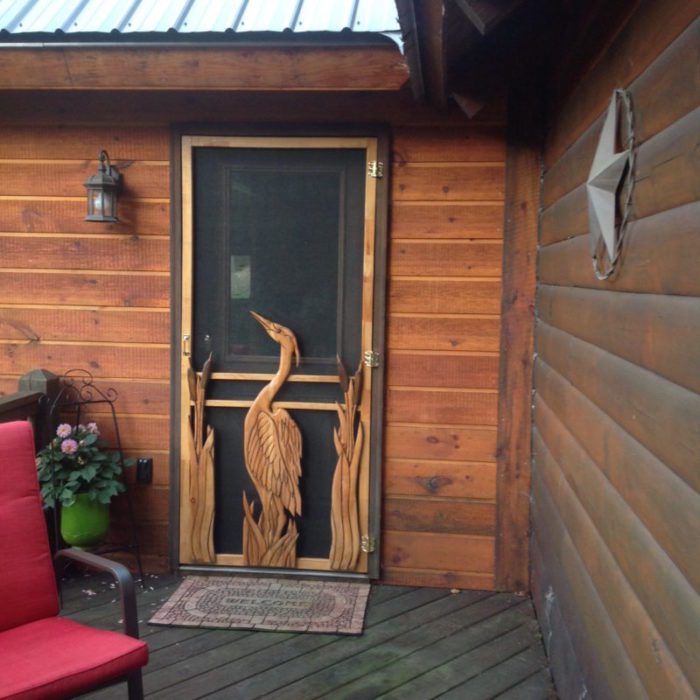 Carved wood screen door with heron and cattails